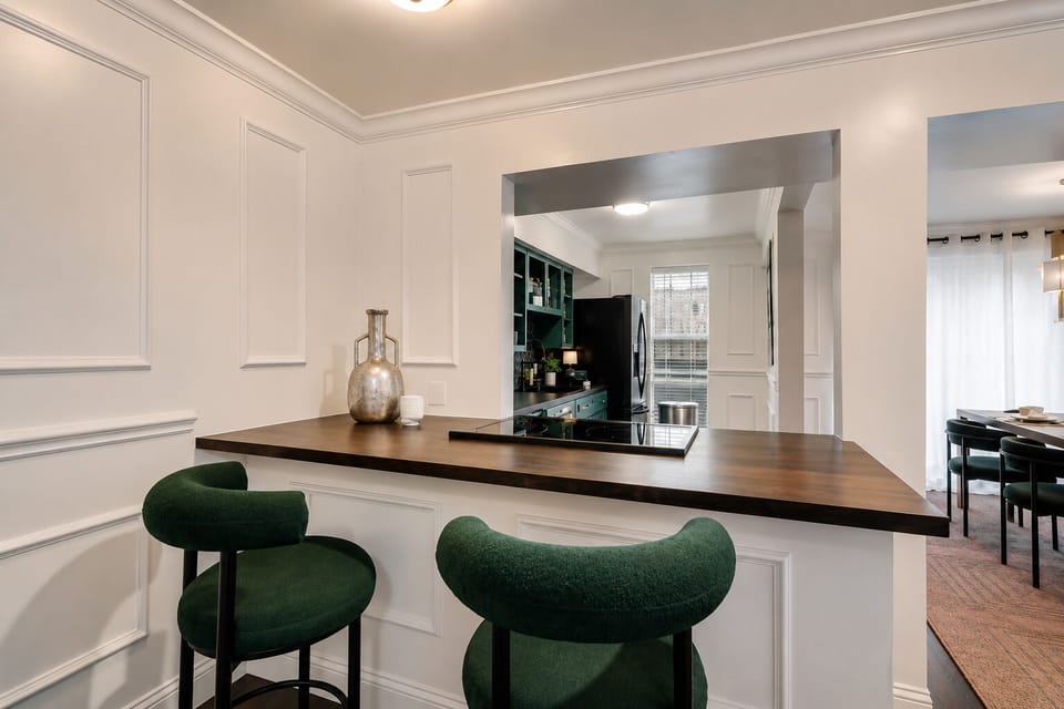 Stylish bar seating with plush green chairs at the kitchen island, perfect for casual meals or chatting with the chef.