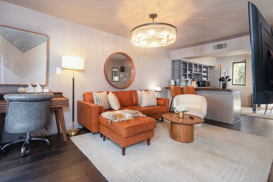 Open living room with a roomy leather sectional and plenty of seating, plus a large Smart TV for ultimate relaxation and entertainment. 