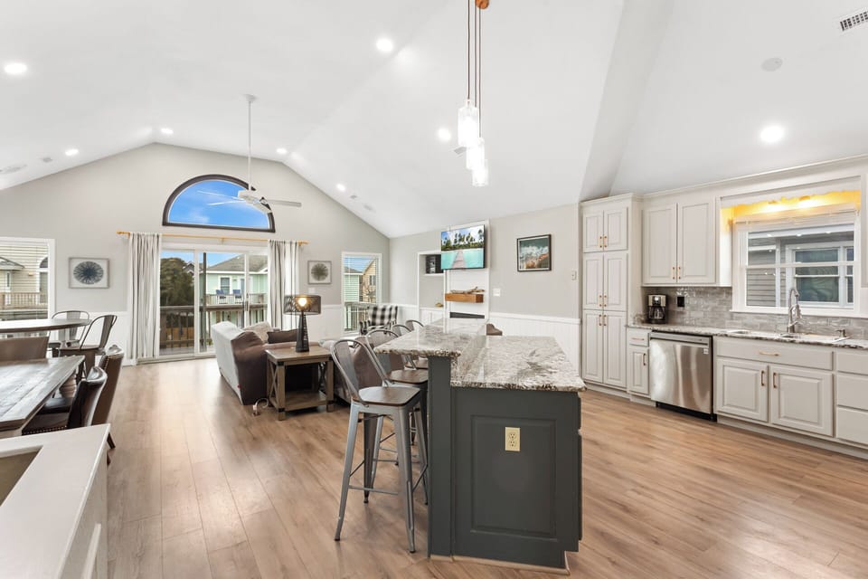 The Top Level of the home features an Open-Concept Living Area with comfortable furnishings, a Flat-Screen TV, and direct access to the Furnished Sun Deck, perfect for soaking up the coastal breeze.