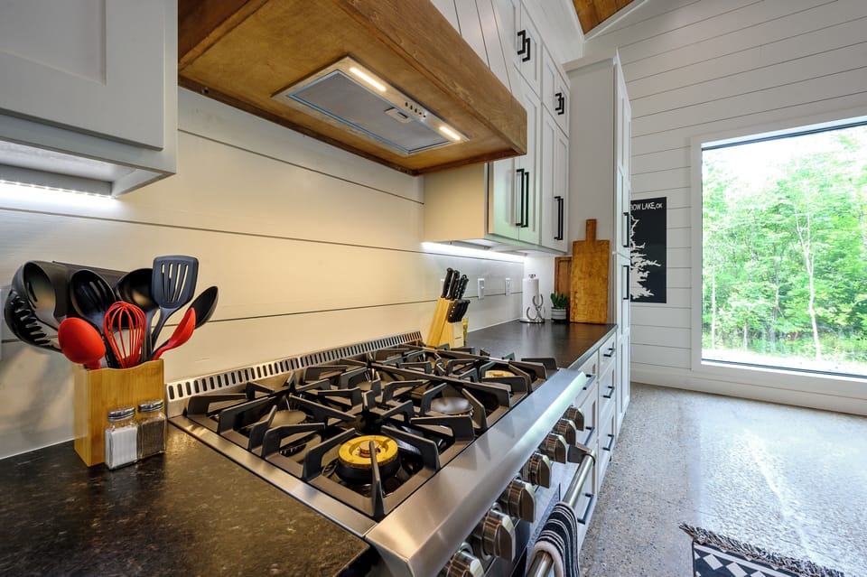 Sleek modern kitchen with a gas stove and stunning forest views. 