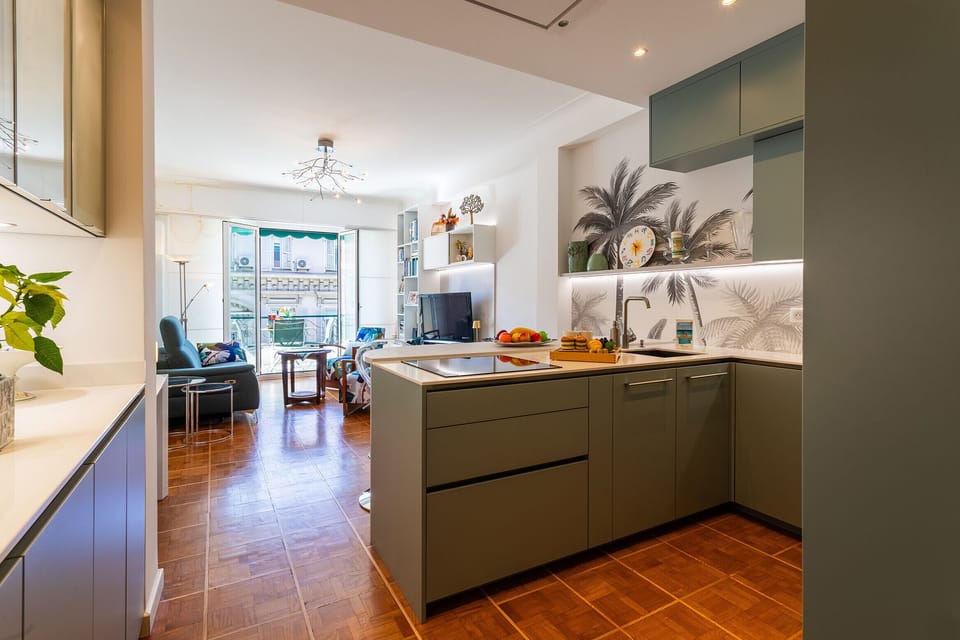 Bright view of the living room and kitchen with a modern island, built-in appliances, and elegant wall decor.