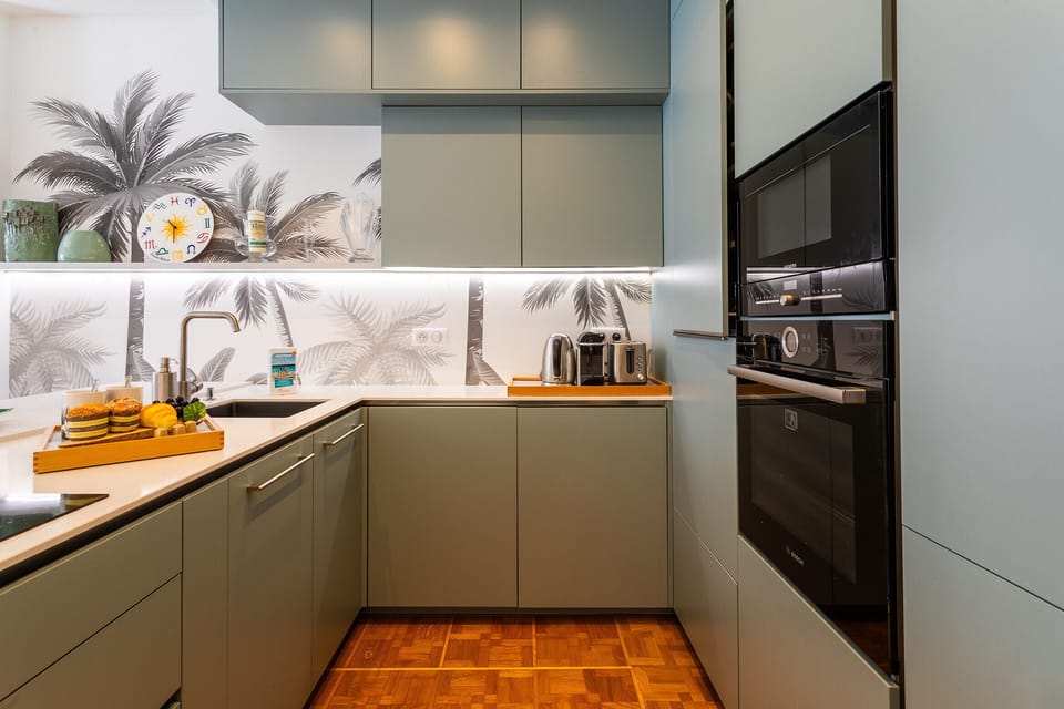Modern kitchen with high-end appliances, elegant decor in soft tones, and tropical motifs for a welcoming atmosphere.