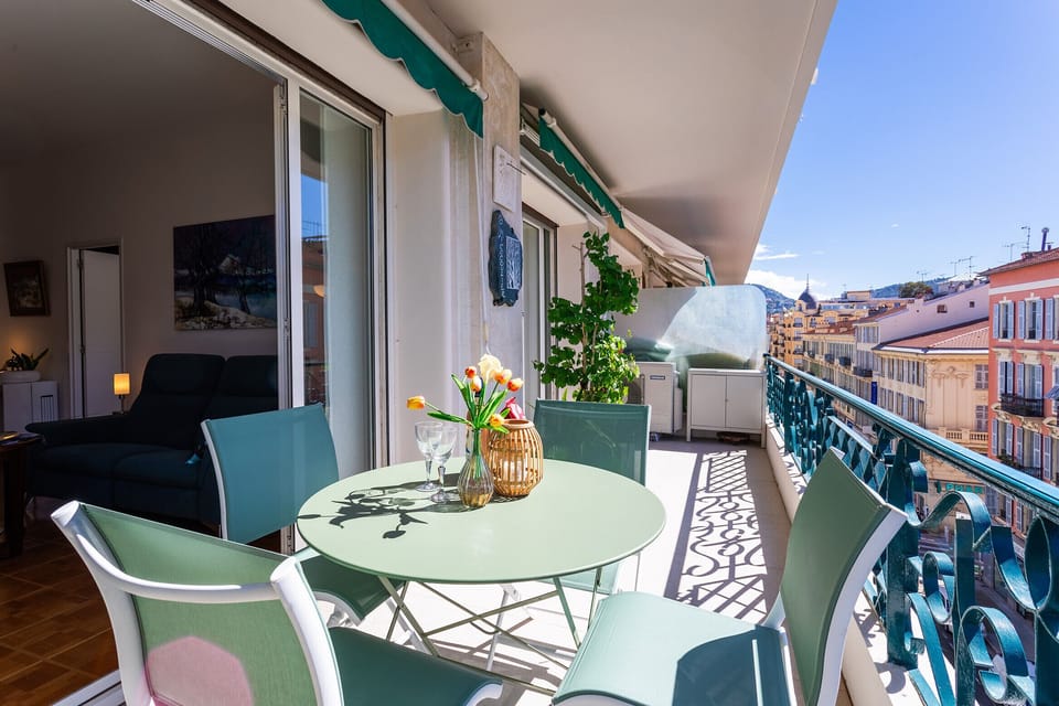 Sunny terrace with a table and comfortable chairs, perfect for outdoor meals with views of Nice’s colorful rooftops and a Mediterranean vibe.