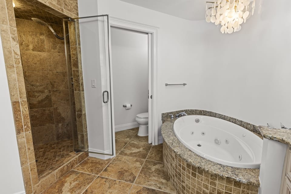 Step into your private spa-like bathroom featuring a luxurious jetted tub and spacious walk-in shower with natural stone details.