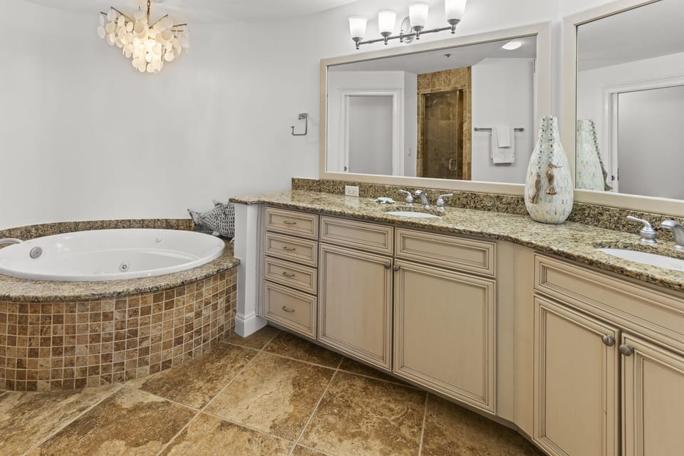 Indulge in your private spa retreat with granite counters, jetted tub, and elegant chandelier creating the perfect relaxation sanctuary.