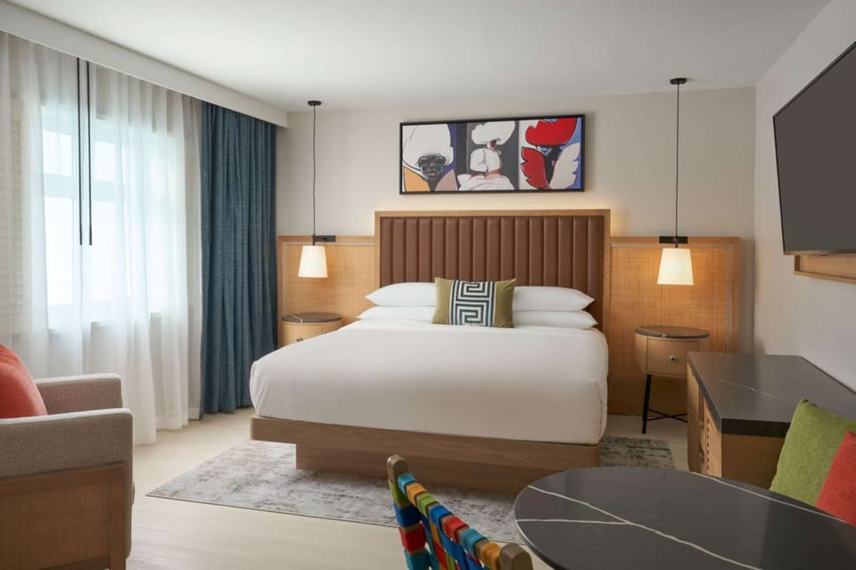 King bed room with soft lights, chair, table and large window