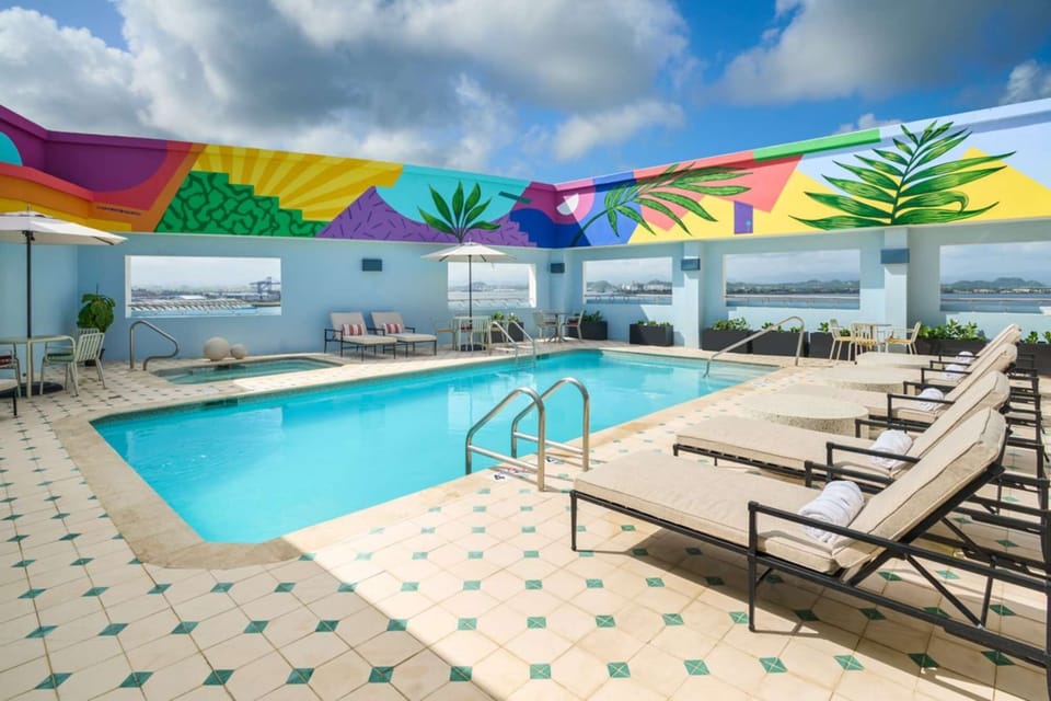Pool area with lounge chairs and bright mural on the wall