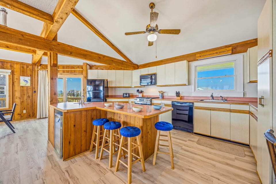 Cook your favorite meals in this spacious kitchen featuring exposed wood beams, a breakfast island, and modern appliances.