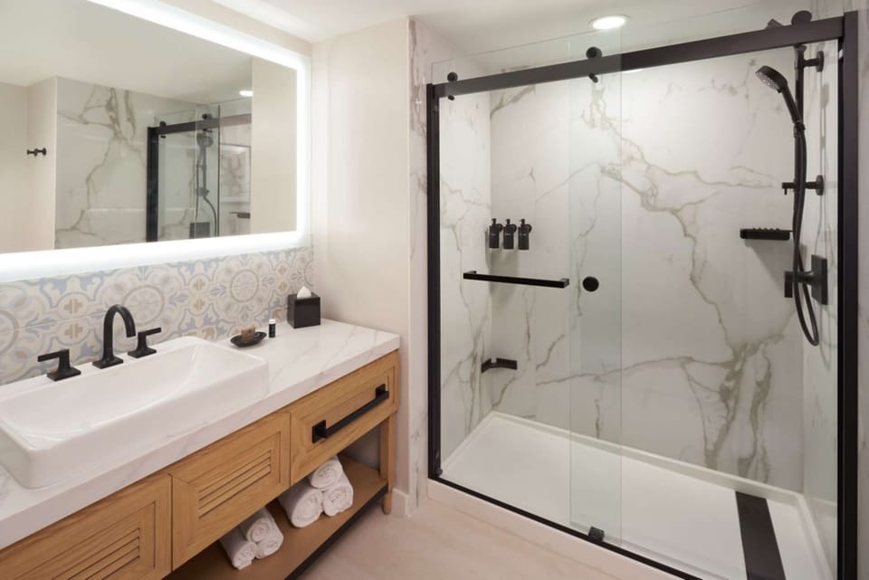 Clean bathroom with sink, mirror light and glass shower area