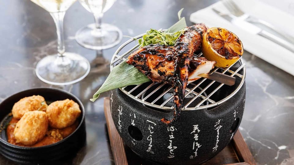 Grilled fish with lemon on small charcoal grill dish