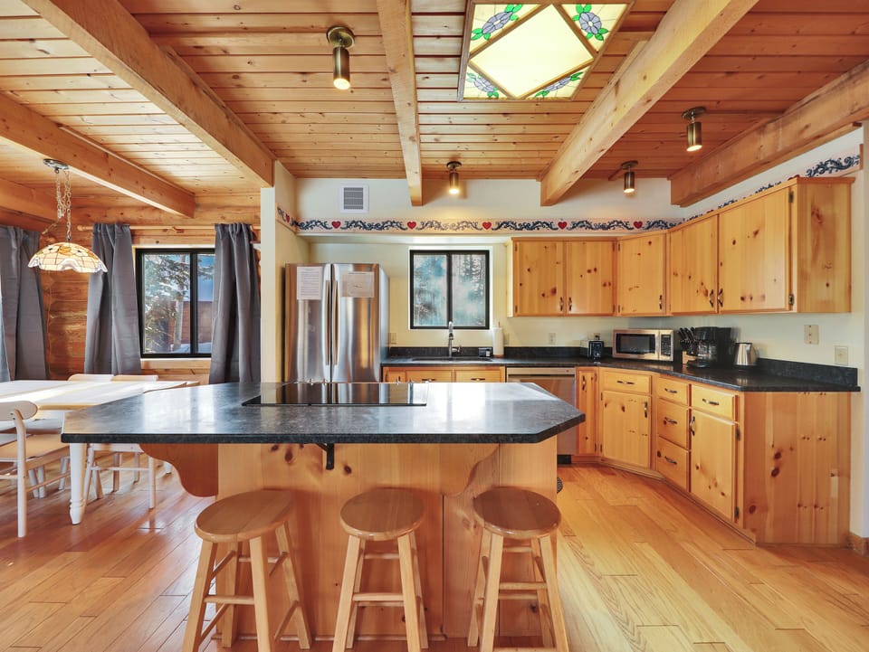 Charming rustic kitchen located on the main floor with a skylight, wooden cabinetry, a functional center island, and counter seating for three.