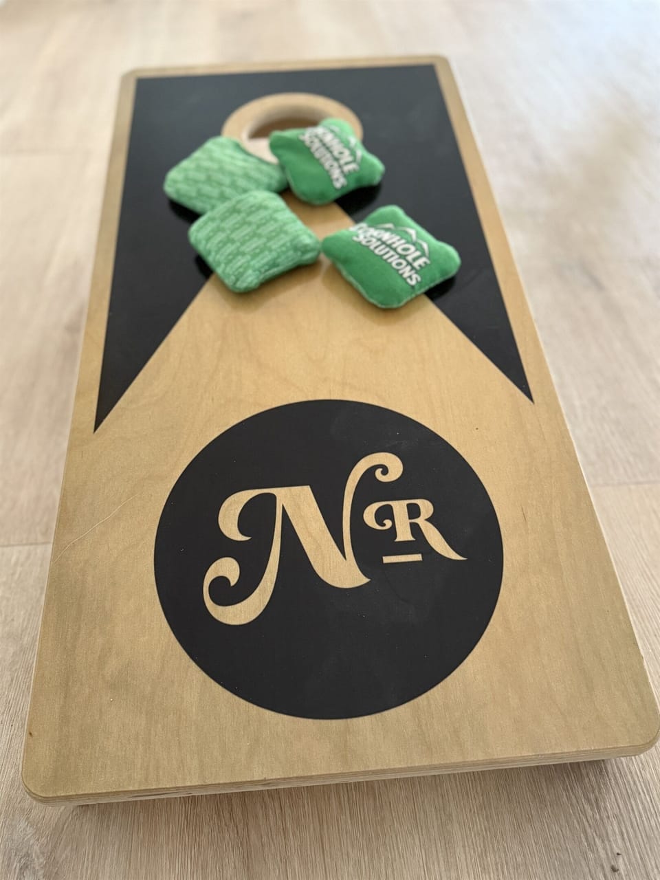 Indoor cornhole in the shared game room — Notestone Reserve branded, separate building a short walk from Whitman