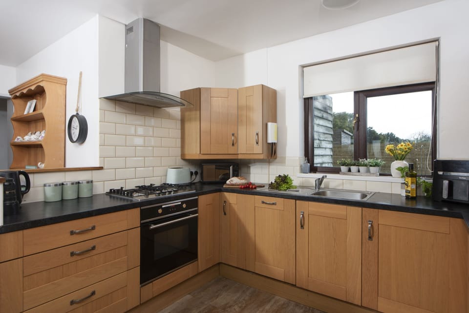 Kitchen with electric oven and hob, dishwasher, microwave, fridge/freezer, kettle, toaster and a range of pans and utensils.