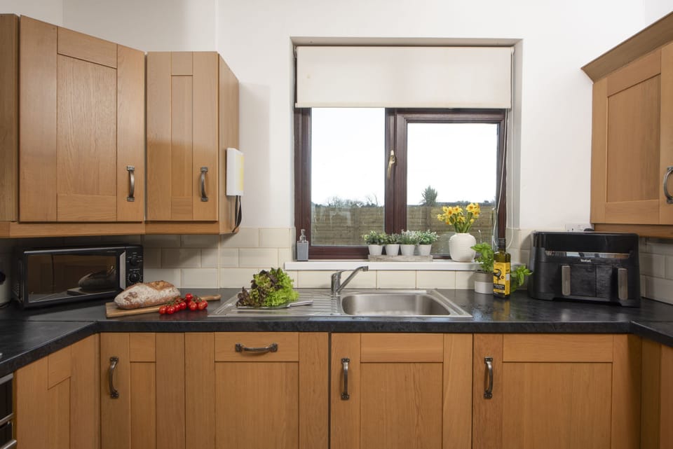 Kitchen with electric oven and hob, dishwasher, microwave, fridge/freezer, kettle, toaster and a range of pans and utensils.