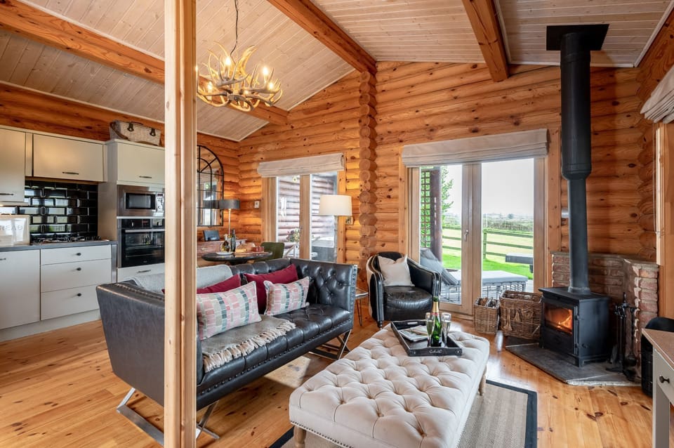 Spacious open-plan living and dining area with log interior, kitchen and wood burner in Spindrifter cabin.