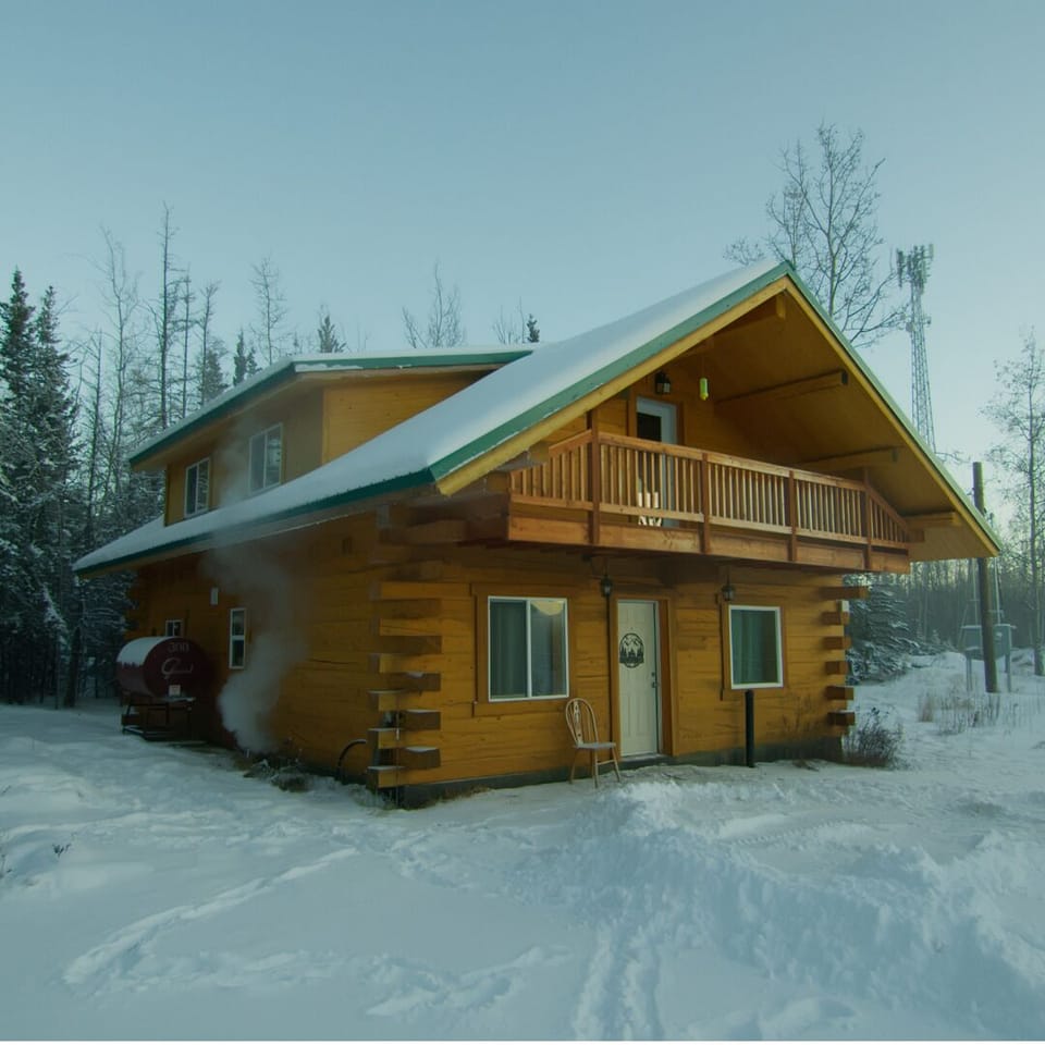 Cozy two-story log cabin with balcony in a peaceful snowy forest escape