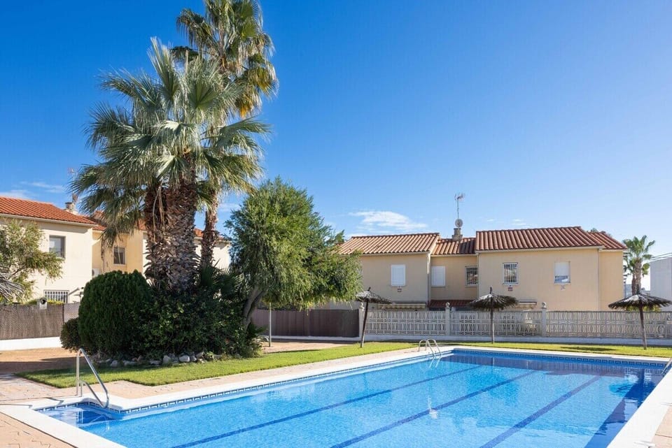 Inviting pool area with lush palm trees and sunlit surroundings for ultimate relaxation.
