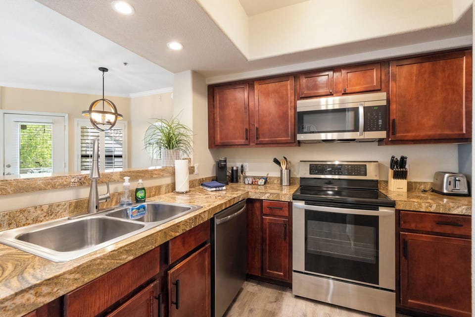Fully stocked kitchen with oven, microwave, coffee maker, and utensils.
