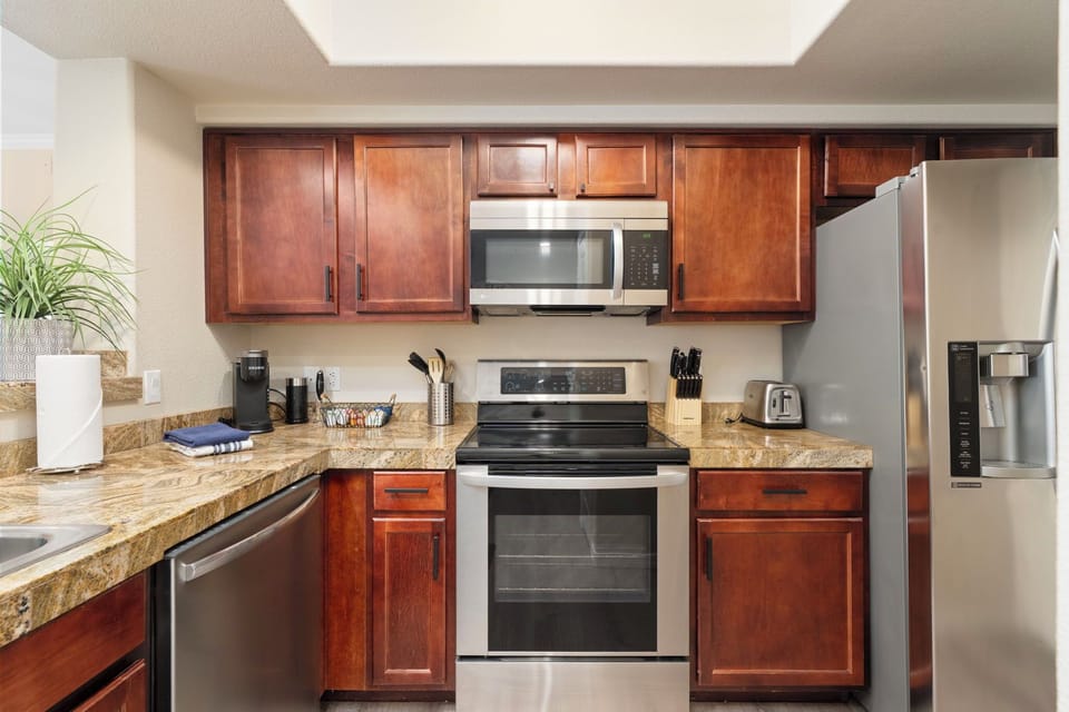 Fully stocked kitchen with oven, microwave, coffee maker, and utensils.