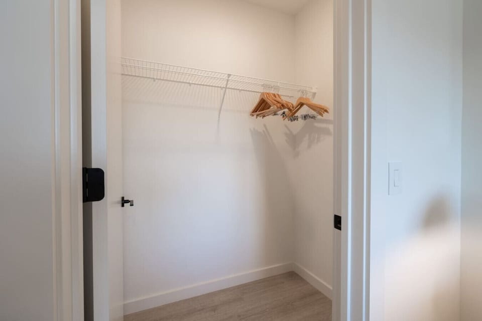 This spacious walk-in closet features a clean and organized design with a hanging rod and shelving, providing ample storage space and a tidy environment.