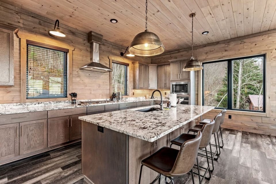 This modern kitchen blends rustic charm with upscale finishes. Featuring a spacious island, granite countertops, stainless steel appliances, and ample seating, it`s perfect for prepping meals and gathering with loved ones while enjoying the mountain