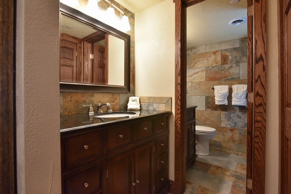 Rustic-style bathroom with stone accents, a large vanity, and a warm, inviting ambiance.