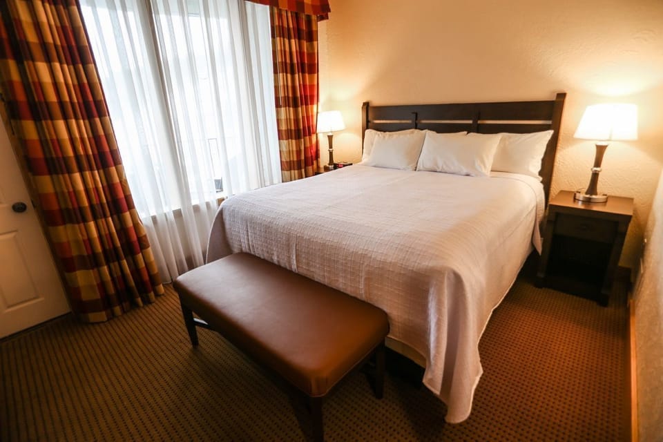 Cozy bedroom with a plush bed, soft lighting, and elegant curtains creating a warm, inviting ambiance.