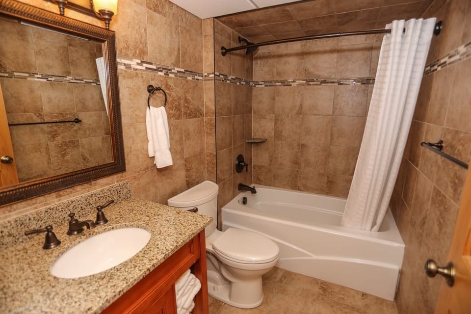 Beautifully designed bathroom with stone tiles, a spacious vanity, and a relaxing shower-tub combination.