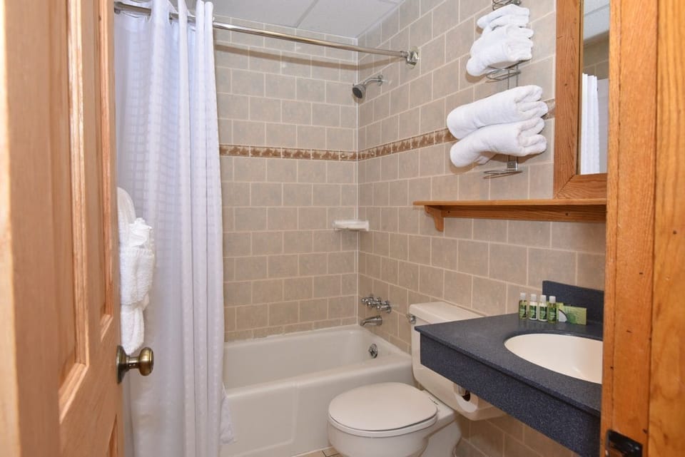Pristine bathroom with a tiled shower-tub combination, ample towels, and thoughtful storage for added convenience.