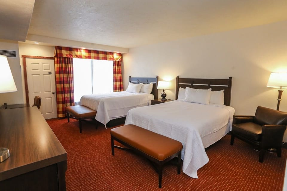 Spacious room with two plush beds, warm lighting, and a cozy seating area, perfect for a relaxing stay.