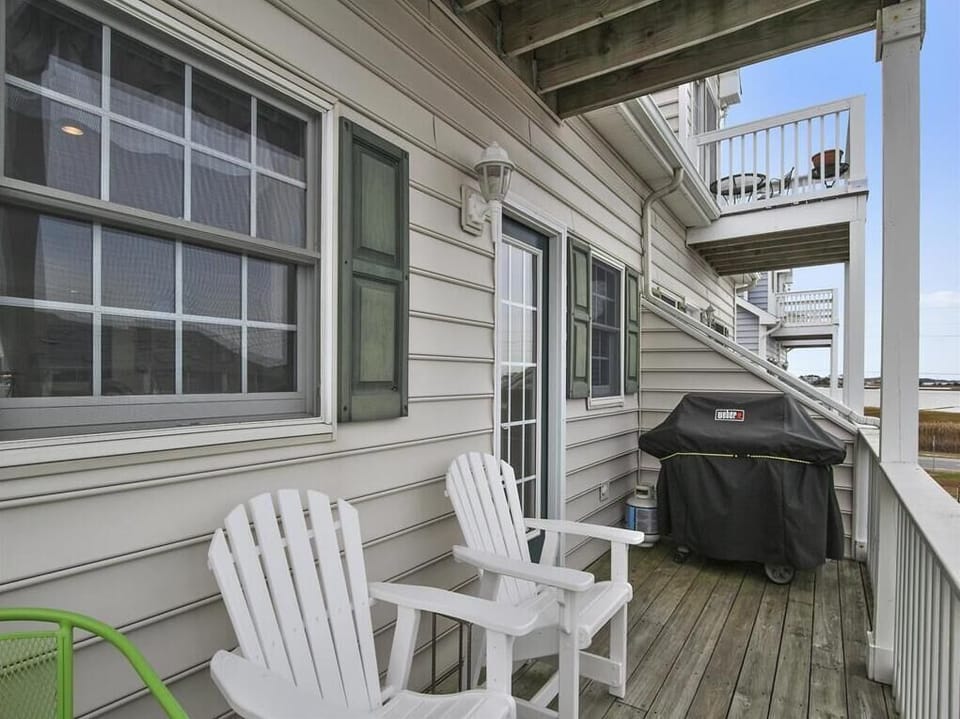 Cozy balcony with Adirondack chairs and a grill, perfect for sunset dinners with a bay breeze.