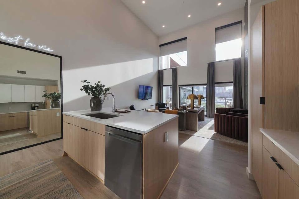 Stylish and functional tall ceiling kitchen with stainless steel appliances, full size mirror and natural wood accents.