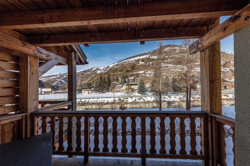 A covered wooden balcony with stunning views of the surrounding snow-capped mountains.