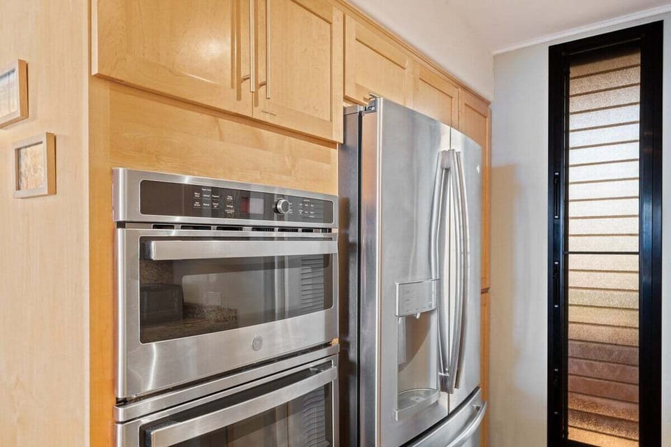 Modern stainless steel appliances including double oven and French-door fridge