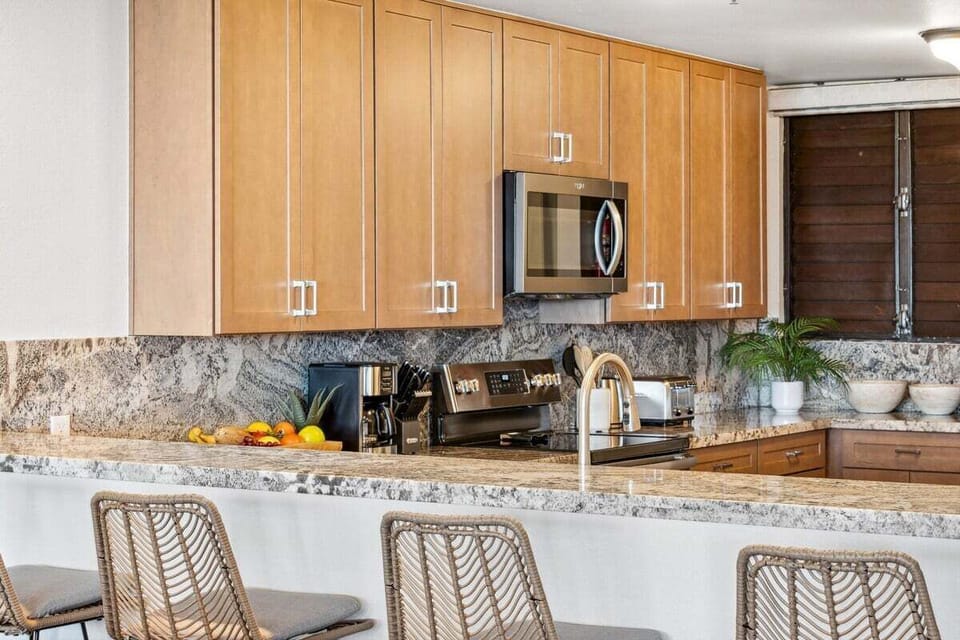 Modern kitchen with light wood cabinetry, granite counters, and stainless appliances, recessed lighting brightening the space.