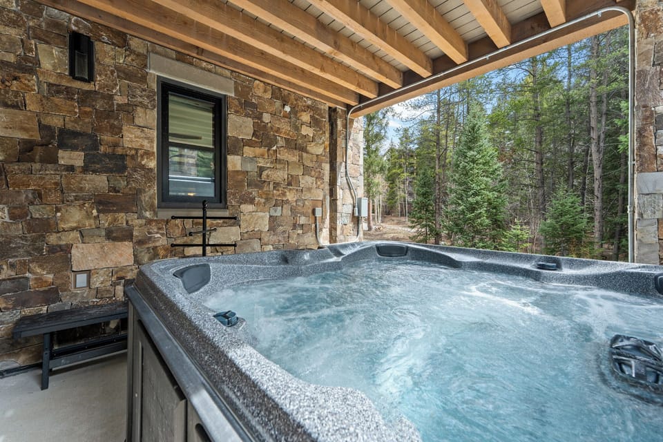 Soak in your private hot tub under the timber-beamed patio, surrounded by towering pines and the peaceful sounds of nature—your perfect mountain retreat.
