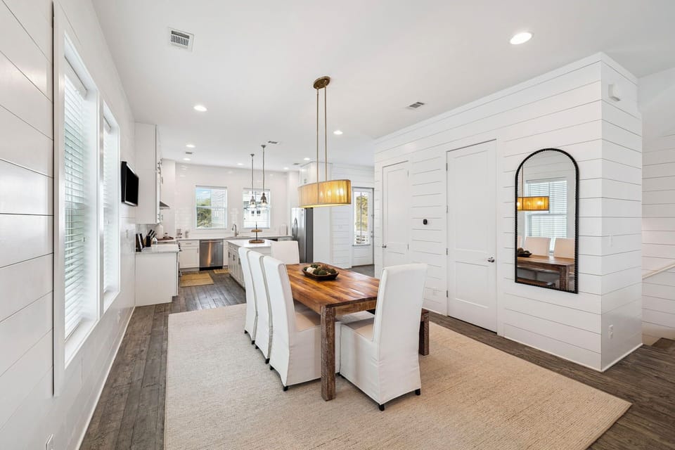 Gather around the elegant dining table in this bright, open space where white shiplap walls and warm wood create the perfect backdrop for memorable meals.