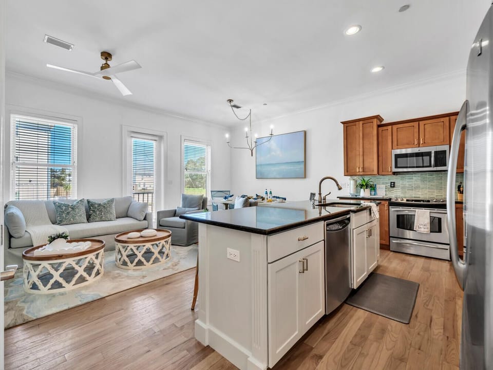 Relax in your bright open-concept space where the fully equipped kitchen flows into a coastal-themed living area with ocean views through three windows.