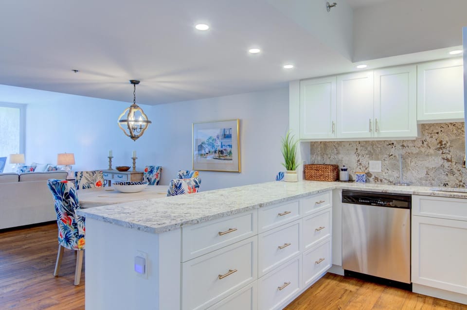 Granite countertops stretch across the kitchen island with white cabinetry and stainless steel dishwasher below.