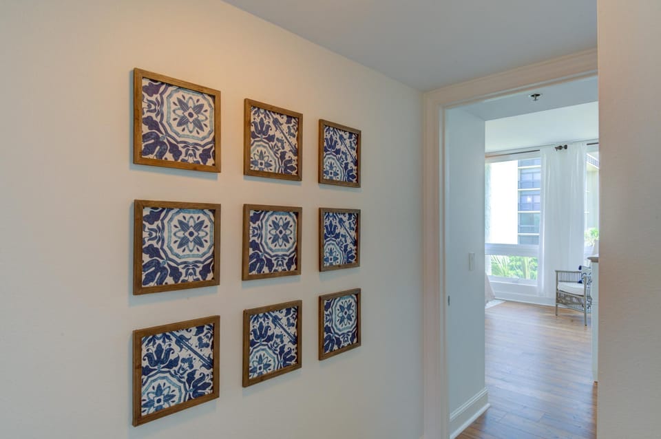 Navy and white patterned tile artwork in wood frames lines the hallway wall near the bedroom entrance.