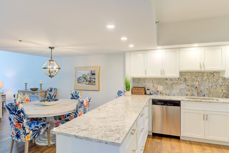 Kitchen features white cabinetry, speckled granite countertops, stainless steel dishwasher, and floral-upholstered dining chairs.