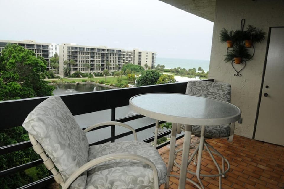 Balcony features a round glass-top table with two cushioned chairs on terracotta tile flooring.