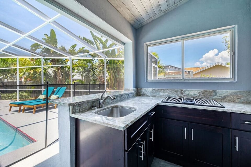 Enjoy outdoor cooking and drinks by the pool in this shaded summer kitchen.