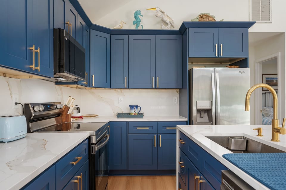 Sleek navy cabinetry, quartz counters, and gold fixtures make this kitchen both chic and practical.