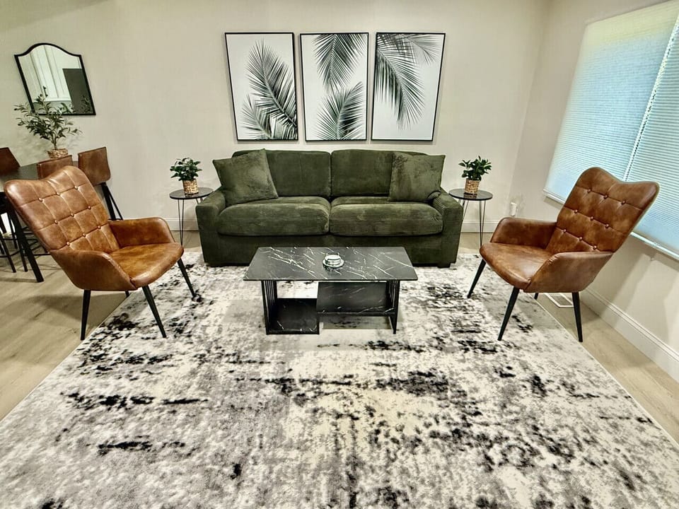 Cozy living room featuring a comfy pull-out couch, perfect for relaxation or guests. Bathed in natural light from large windows, this inviting space is ideal for gatherings and peaceful evenings, enhanced by stylish decor and ample seating.