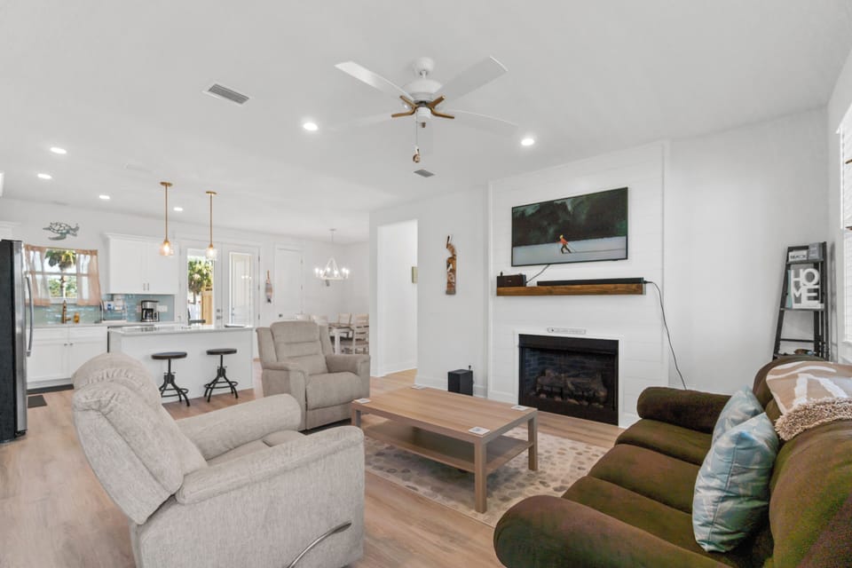 Relax in your spacious living area featuring plush seating, a cozy fireplace, and open-concept design flowing into the fully equipped kitchen.