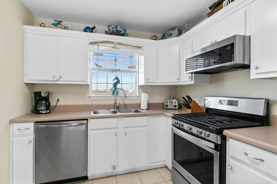 Whip up your favorite meals in this well-equipped kitchen with stainless steel appliances and cheerful seahorse window décor.