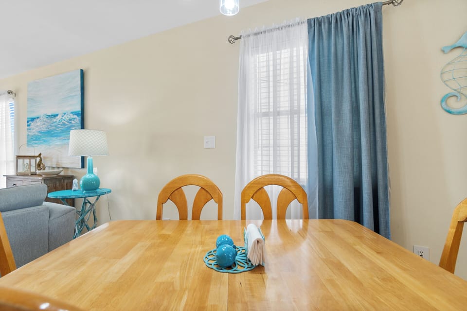 Your bright dining space features ocean-inspired coastal decor and natural light, creating the perfect spot for morning coffee or evening meals.
