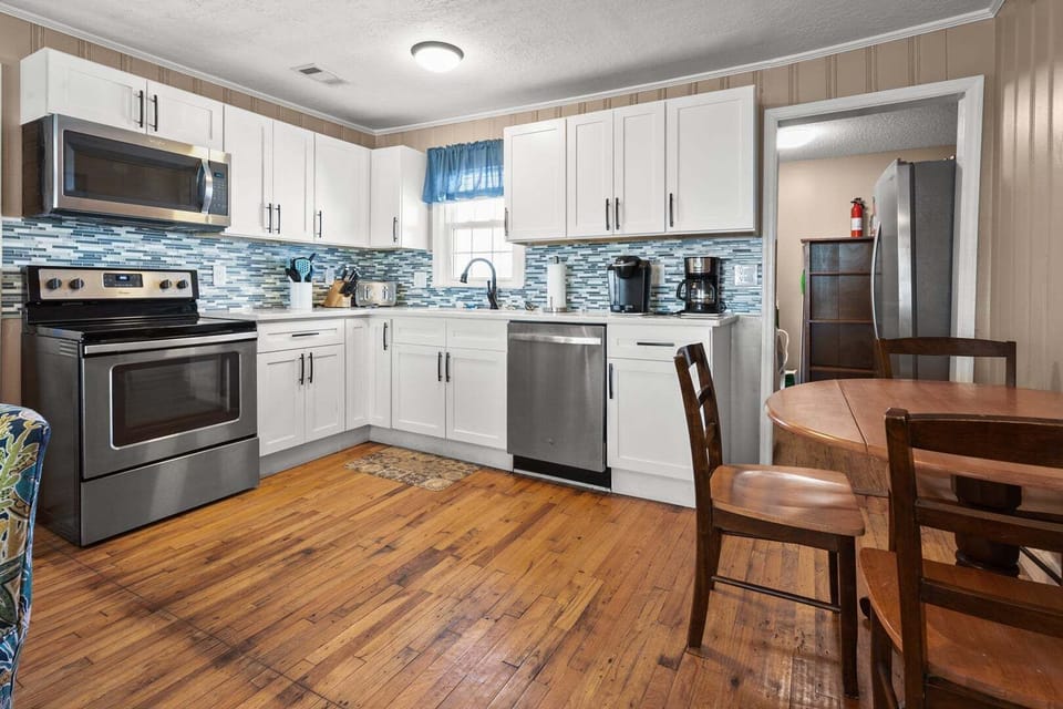 Kitchen with white cabinetry and a blue backsplash beside the dining table at Rising Tide, Cherry Grove