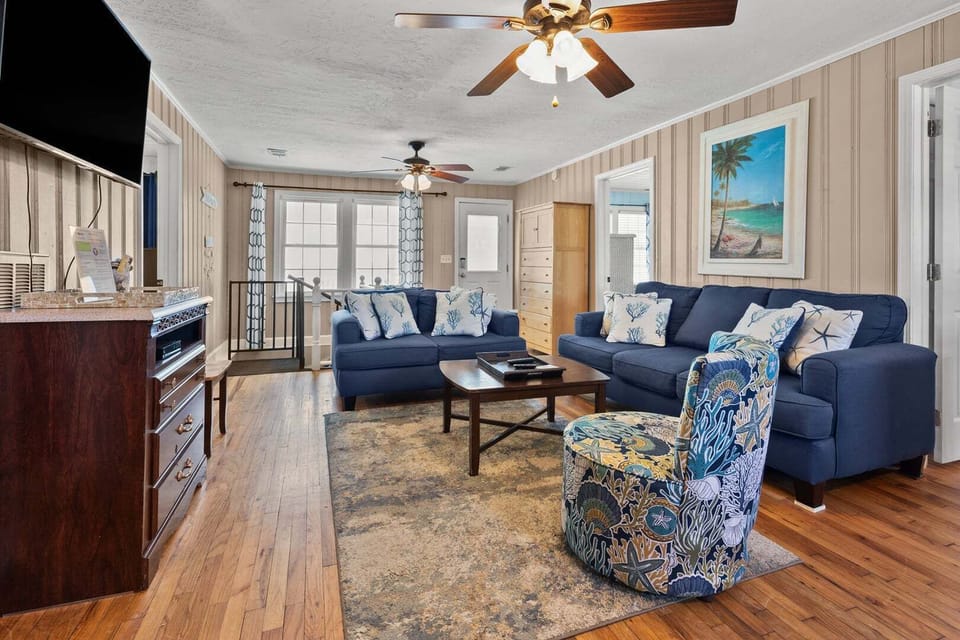 Blue sectional seating and coastal art in the living area at Rising Tide, a Cherry Grove beach house rental